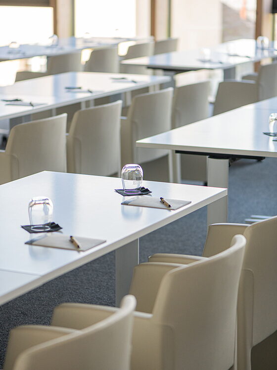 Gedeckter Sitzungstisch: Notizblock, Stift und Glas